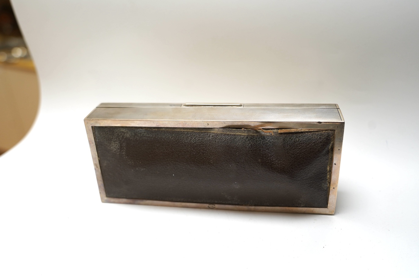 A George V engine turned silver mounted rectangular cigarette box, London, 1935, 21.7cm. Condition - poor